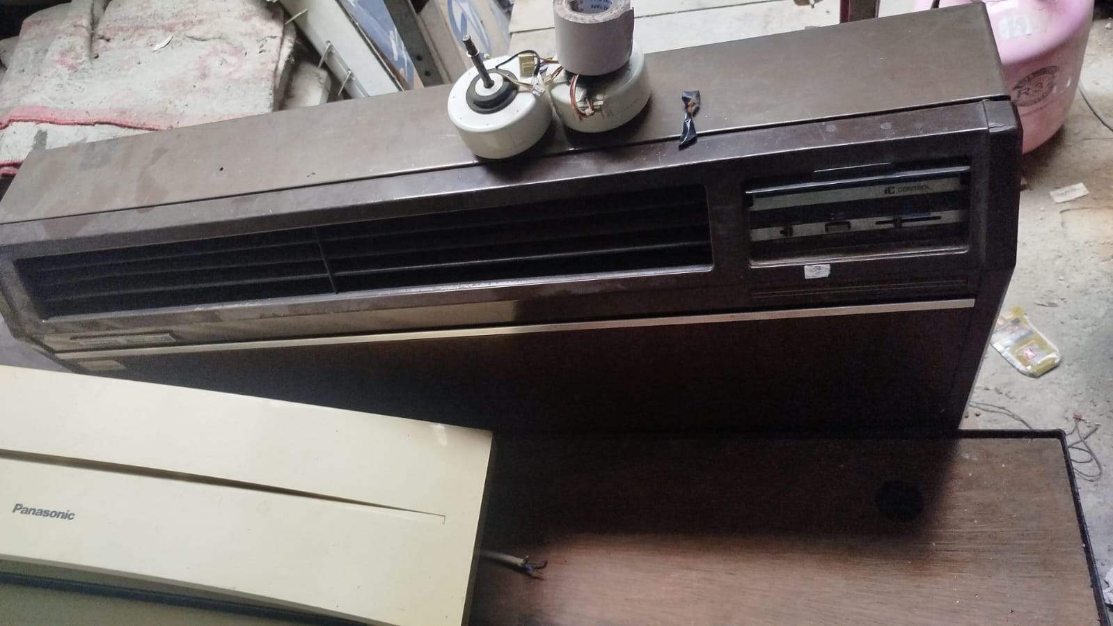 Professional technician servicing a wall-mounted air conditioner, checking refrigerant with manifold gauge, wearing safety gear, Indonesian home interior, realistic photo.
